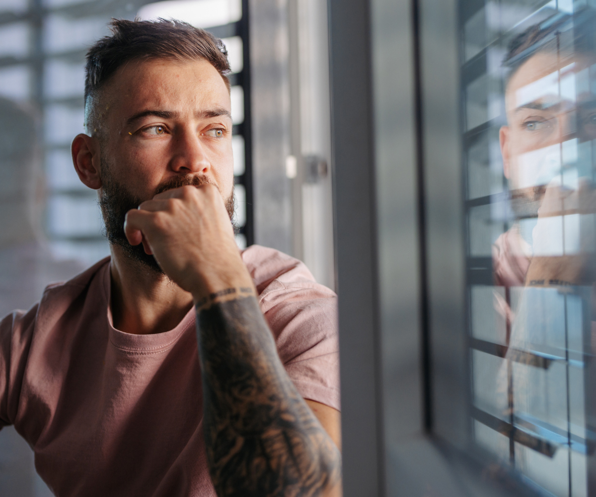 A man stares out of the window as he ponders whether low testosterone causes anxiety.